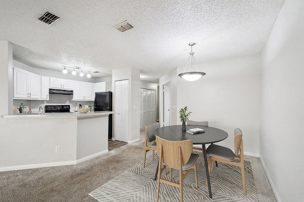 Model Dining Room with Carpet and View of Kitchen at Westland Park Apartments in Jacksonville, FL.