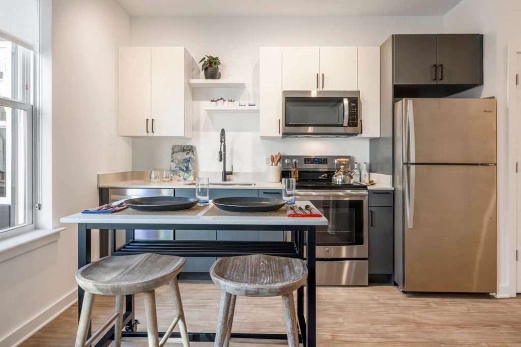 Model kitchen with stainless steel appliances and a counter with two stools
