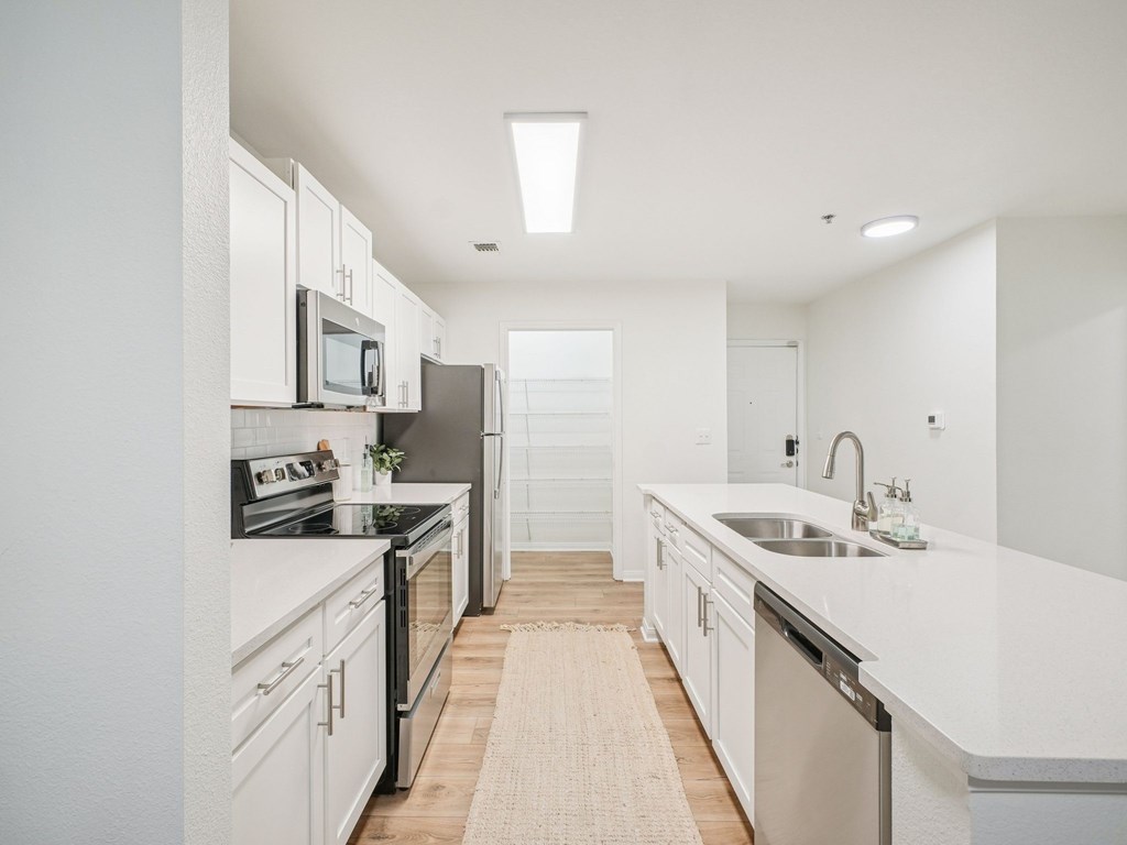 A modern kitchen with white cabinets and stainless steel appliances.