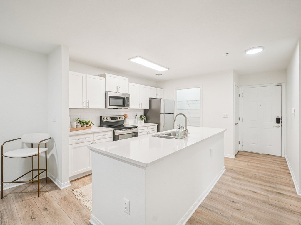 A kitchen with white cabinets and a white island.
