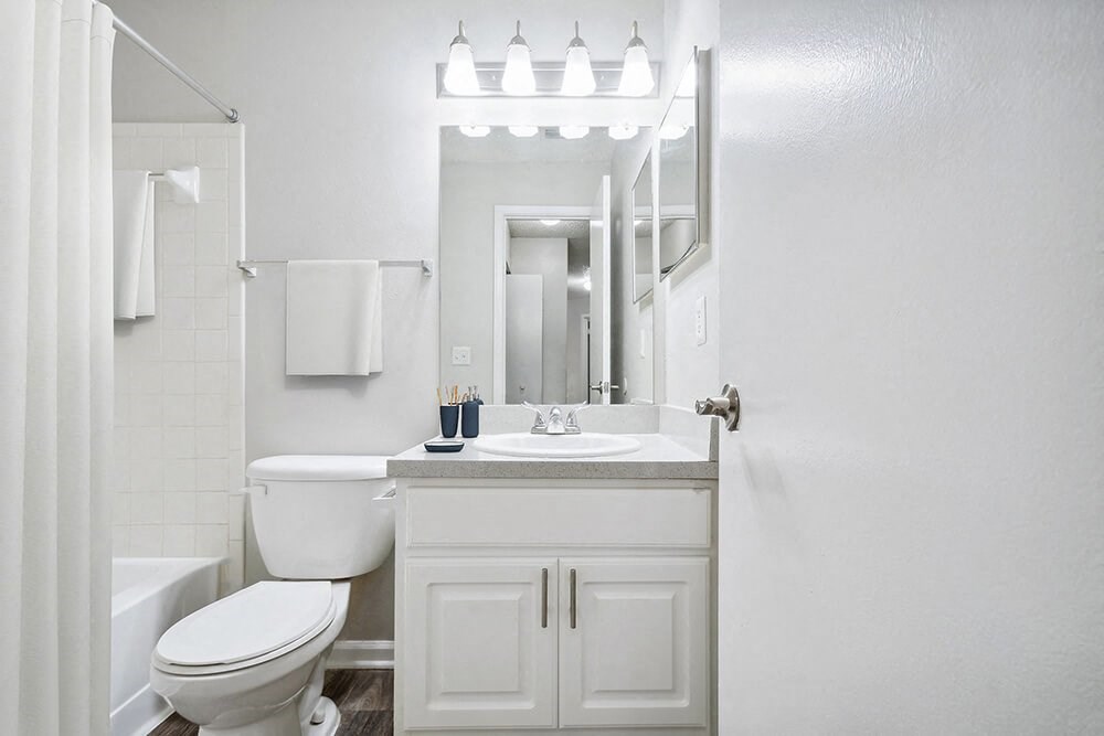 Model Bathroom with White Cabinets, Wood-Style Flooring and Shower/Tub at Westland Park Apartments in Jacksonville, FL.