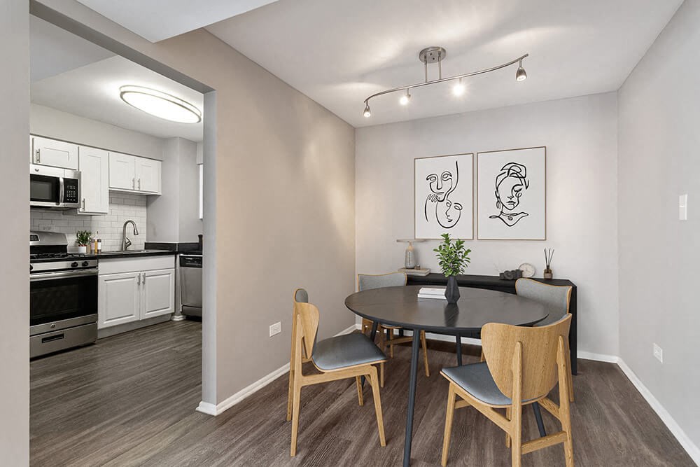 Model Dining Room with Wood-Style Flooring and View of Kitchen at Midpointe Apartments in Chicago, IL.