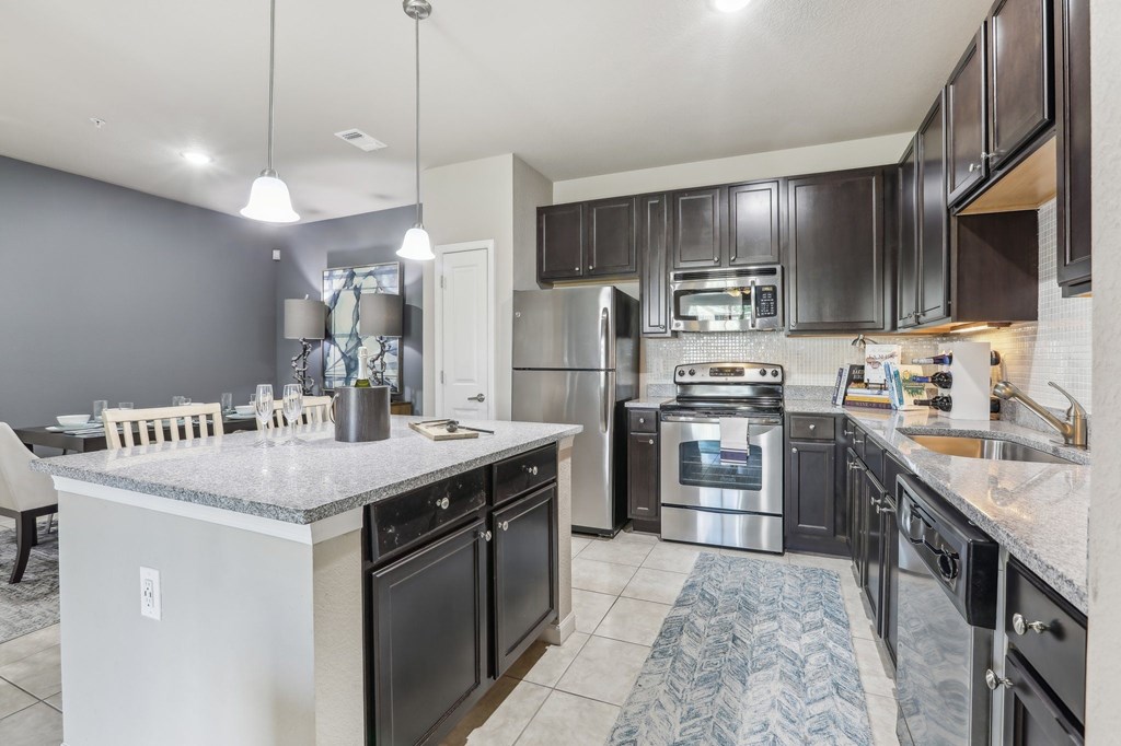 Model kitchen with a large island and stainless steel appliances.
