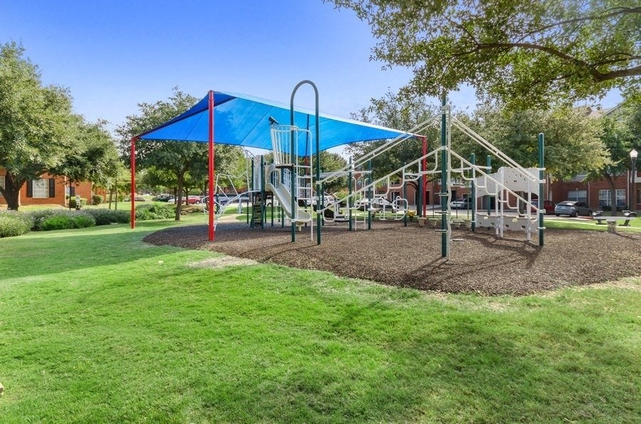 Playground on sand surrounded by well kept grass