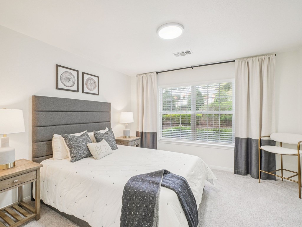 A bedroom with a large bed and a window with curtains.