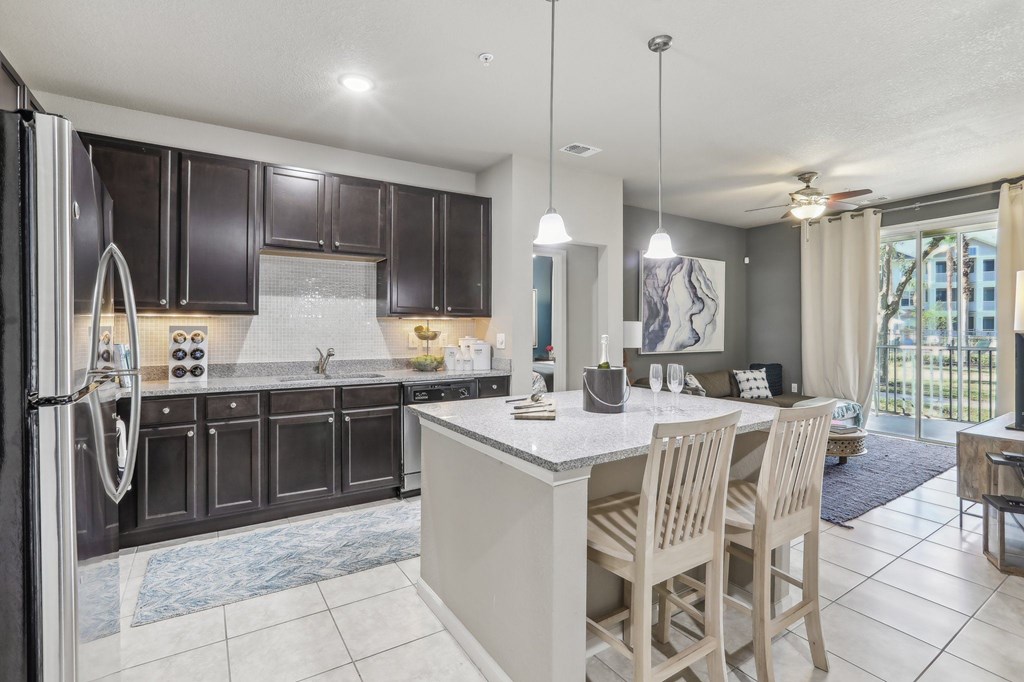 Model kitchen with a large island and wooden chairs.