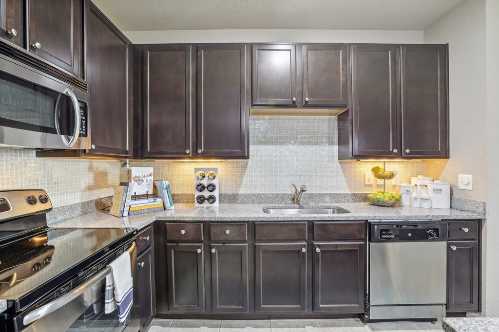 Model kitchen with dark brown cabinets and stainless steel appliances.