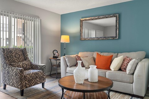 A living room with a leopard print chair, a white couch, and a round table with vases on it.