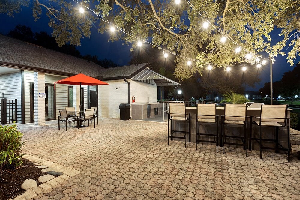 Outdoor BBQ Area with Furniture and Fairy Lights at Carrollwood Station Apartments in Tampa, FL.