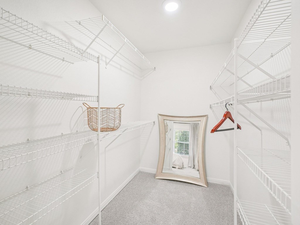 A white closet with a mirror and a basket hanging on the rack.