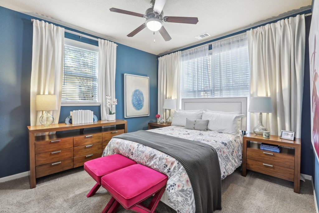 Model bedroom with queen bed and blue accent wall.