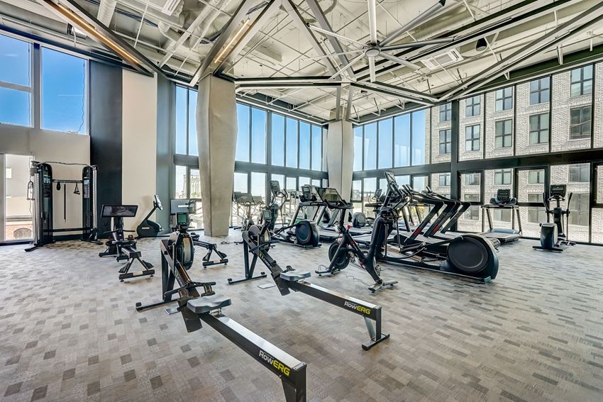 the gym atrium has a large amount of exercise equipment and windows