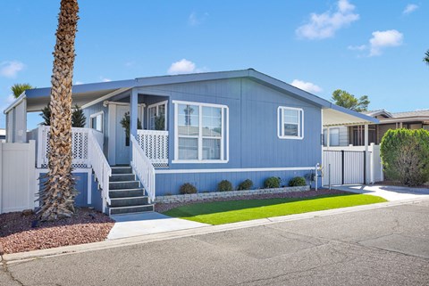 A blue house with a white fence and a palm tree in front.