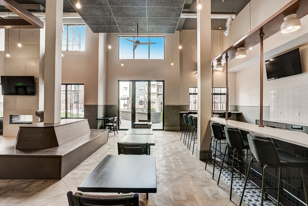 a large lobby with tables and chairs and a bar with chairs