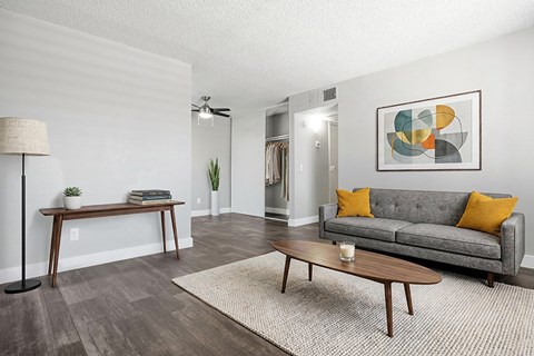 A living room with a grey couch, a wooden table, and a painting on the wall.