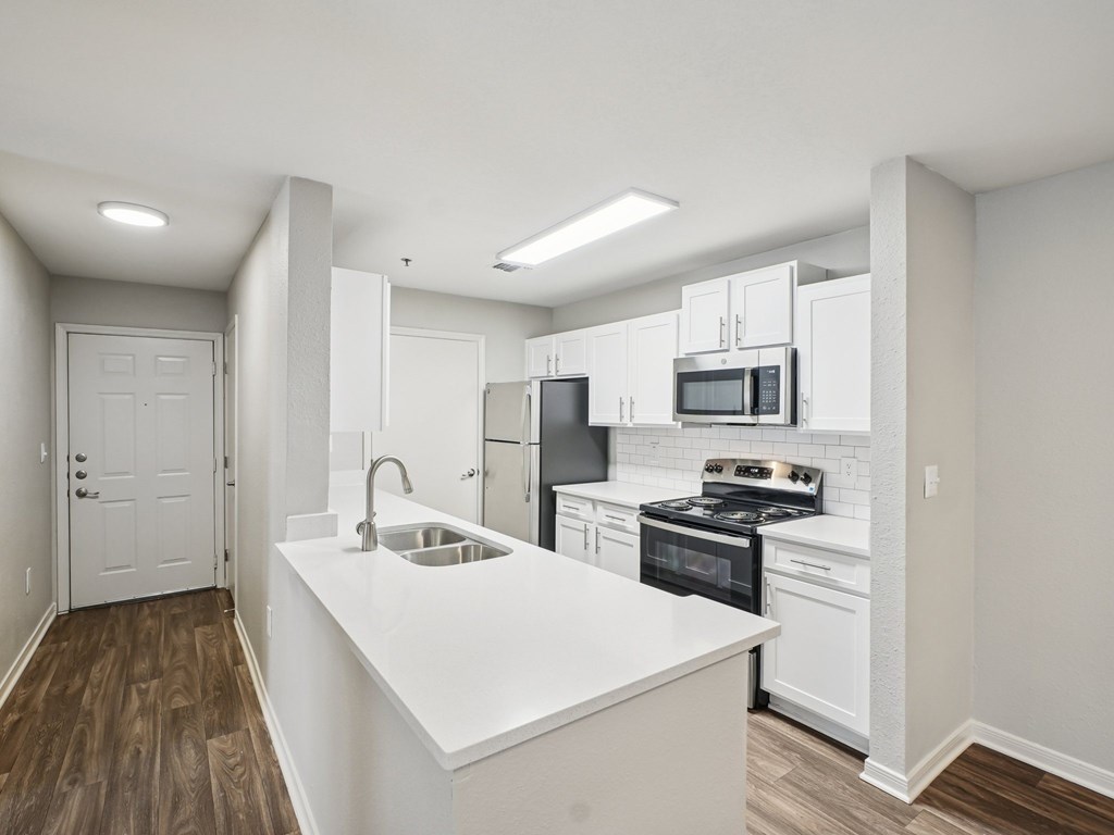 A kitchen with white cabinets and a white island.