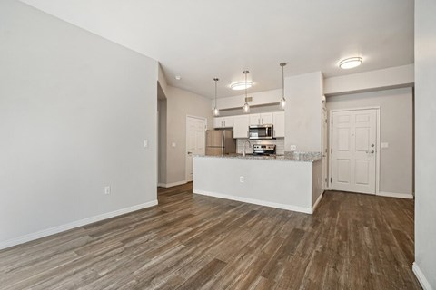 A kitchen area with a white counter and wooden flooring.