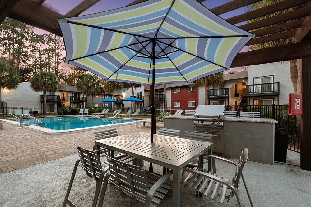 Outdoor BBQ Area with Furniture and Pool View at Heron Walk Apartments in Jacksonville, FL.