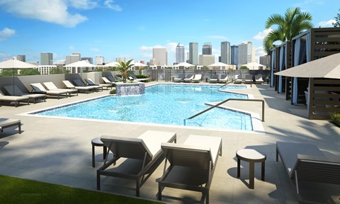 A pool surrounded by chairs and umbrellas with a city skyline in the background.