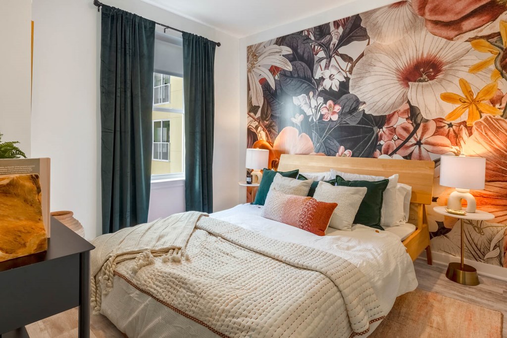 Model bedroom with a bed and a mural on the wall