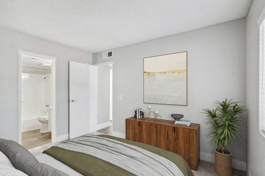 a bedroom with a bed and a potted plant    and a bathroom