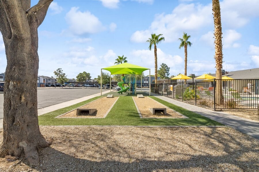 a park with palm trees and cornhole and a playground