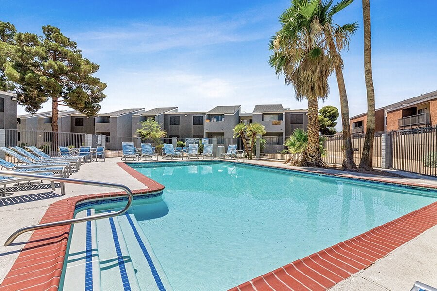a swimming pool with chairs and palm trees
