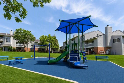 A playground with a blue umbrella and slide.