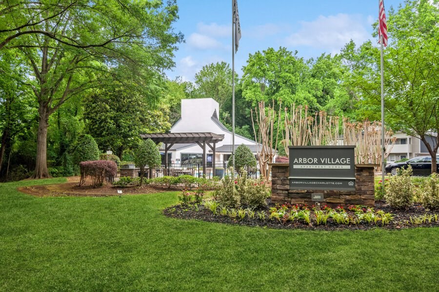 a view of the arbor village sign with a tent and trees in the background