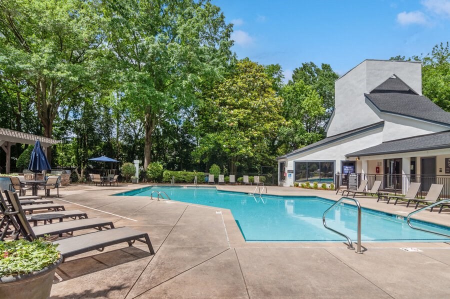 a swimming pool with chaise lounge chairs and a building in the background