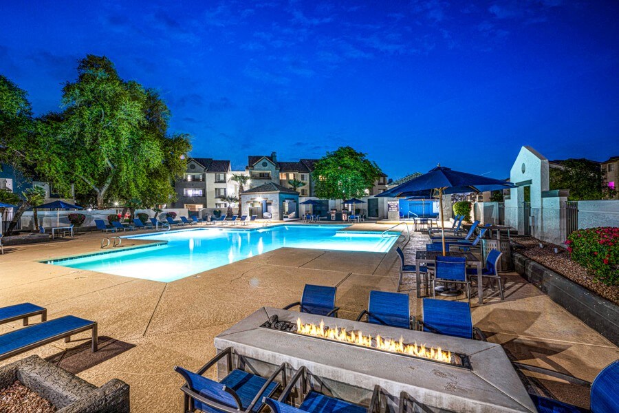 a swimming pool with tables and chairs around it at night at Array South Mountain, Phoenix, Arizona