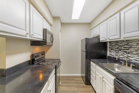A kitchen with black appliances and white cabinets.