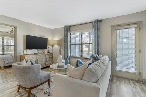 A living room with a grey couch, a chair, and a television.
