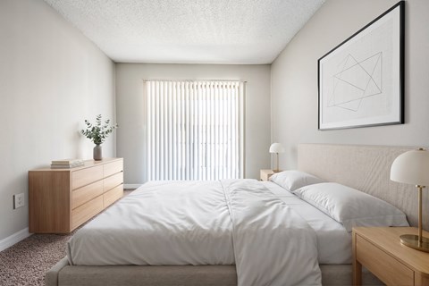 A bedroom with a large bed and a nightstand with a lamp.