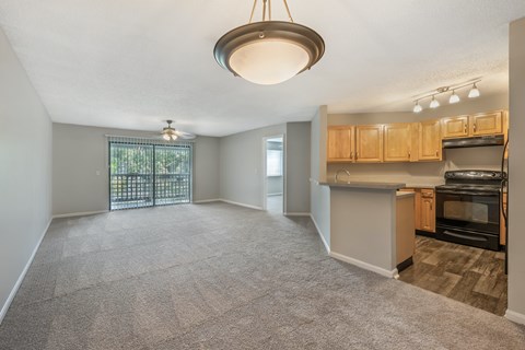 A spacious living area with a kitchenette and a sliding glass door leading to a balcony.