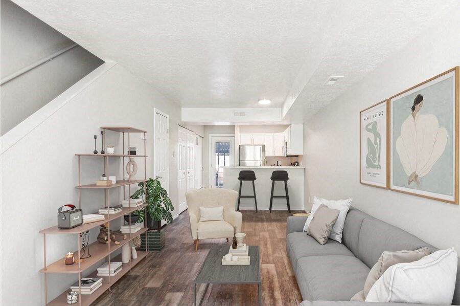 Model living room with a couch and a coffee table and stairs leading up to the 2nd floor.