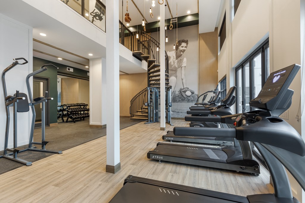 a gym with treadmills and stairs and a mural on the wall