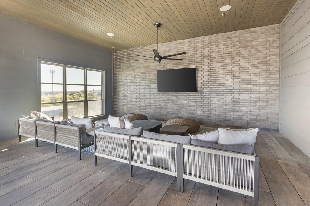 a living room with a couch and a tv on a brick wall