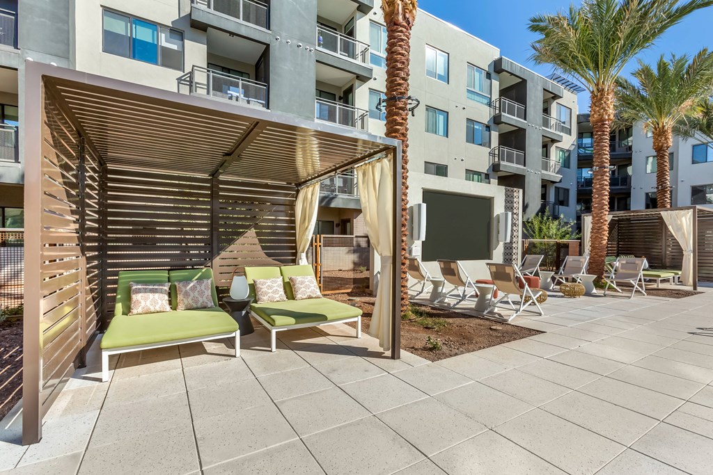 a patio with lounge chairs and a table in front of an apartment building