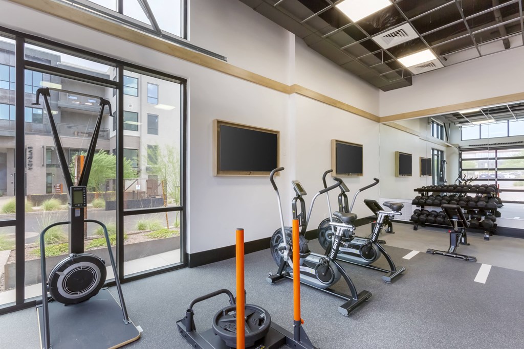 a gym with weights and cardio equipment and a window