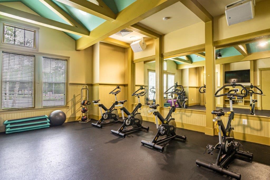 Resident fitness center with a row of exercise bikes and mirrors on the wall at Bridges at Crosstown in Tampa, FL