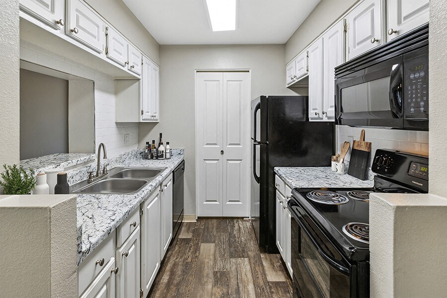 a kitchen with white cabinets and black appliances