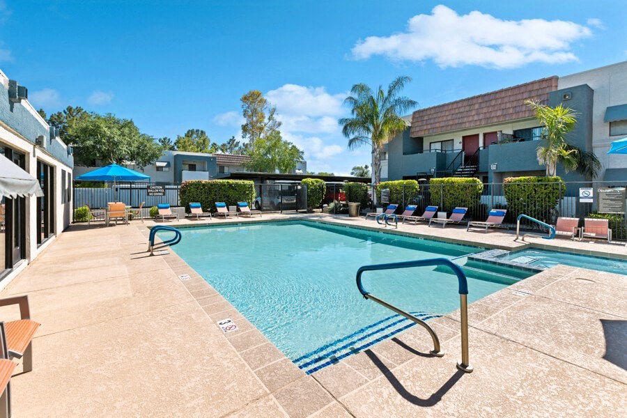 a swimming pool with lounge chairs and umbrellas in front of a building