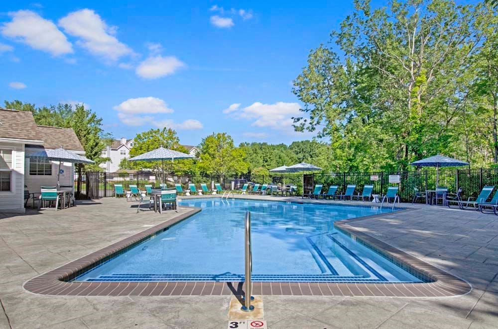 a resort style pool with lounge chairs and umbrellas