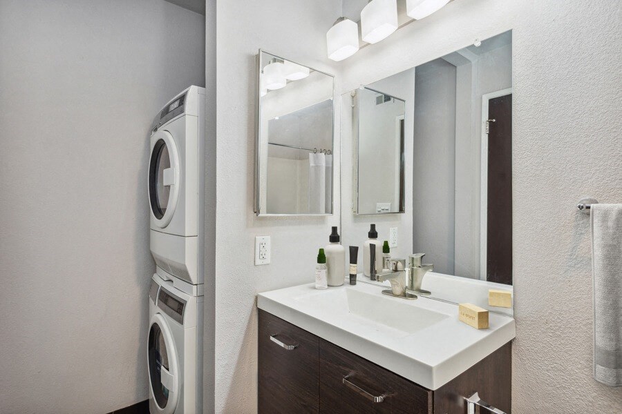 a bathroom with a sink and mirror next to a washer and dryer