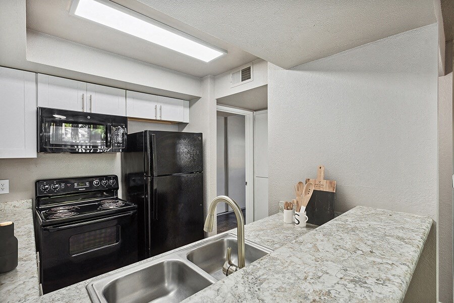 a kitchen with granite countertops and black appliances