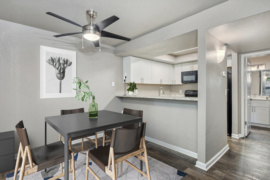 a dining area with a table and chairs and a ceiling fan