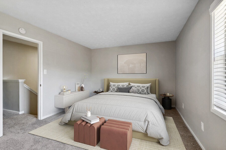 Model apartment bedroom with a large bed and a carpeted floor