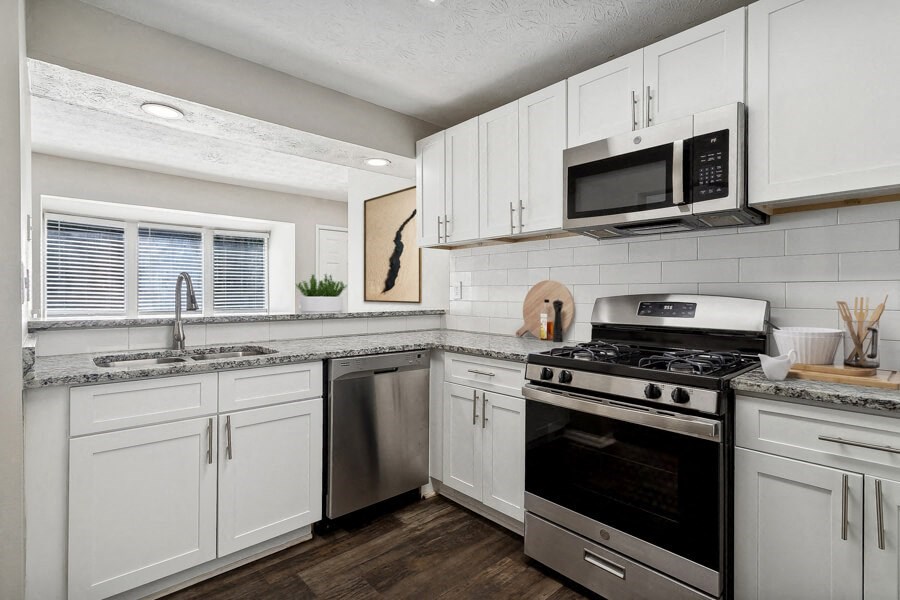 Model apartment kitchen with white cabinets and stainless steel appliances