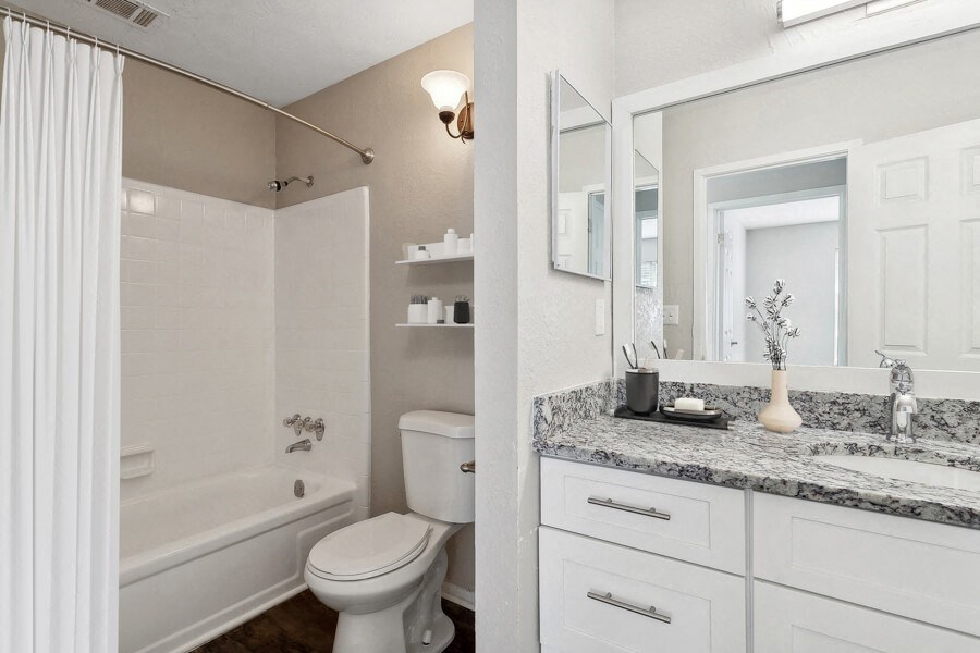 Model apartment bathroom with a shower toilet and sink and a mirror